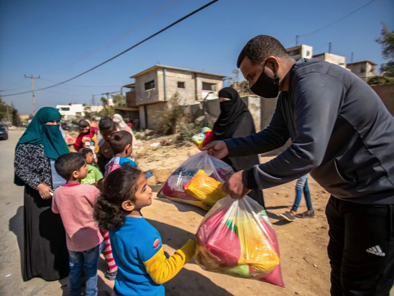 A photo of children in Gaza receiving food packages from HopeForMiddleEast volunteers, showcasing the direct impact of food aid donations.